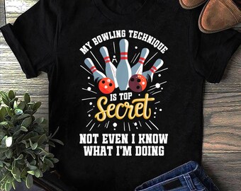 May include: Black t-shirt with a bowling-themed graphic. The design features bowling pins, bowling balls, and the text "My Bowling Technique Is Top Secret, Not Even I Know What I'm Doing."