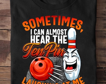 May include: Black t-shirt with a bowling theme. The shirt features the text "SOMETIMES, I CAN ALMOST HEAR THE Ten Pins LAUGHING AT ME" in orange and white. A cartoon bowling pin and ball are also displayed.