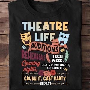 May include: Black t-shirt with a colourful graphic design. The design includes the words "THEATRE LIFE" and other theatre-related terms like "AUDITIONS" and "REHEARSALS". The shirt also features comedy and tragedy masks.