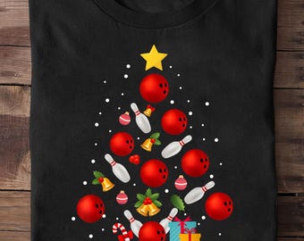 May include: Black t-shirt with a Christmas tree design. The tree is formed from red bowling balls, white bowling pins, gold bells, and a yellow star. Ornaments and a candy cane complete the festive look.
