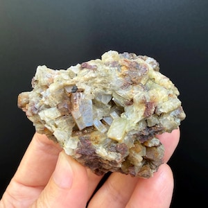 May include: A raw mineral specimen featuring a cluster of translucent, pale yellow and white crystalline structures interspersed with dark reddish-brown, earthy inclusions. The formation has a rough, jagged texture with visible facets.