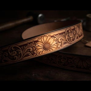 May include: A white ceramic mug with a black handle and the text "But First, Coffee" in a bold, black font. The mug is set against a blurred background, suggesting a cozy setting.