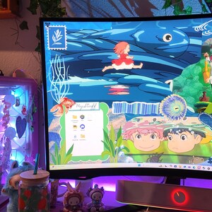 May include: A desktop computer with a colorful animated wallpaper featuring a girl in a red dress running across a blue ocean. A green and white keyboard, a pink cloud-shaped wrist rest, and a glass jar with a straw are in the foreground.