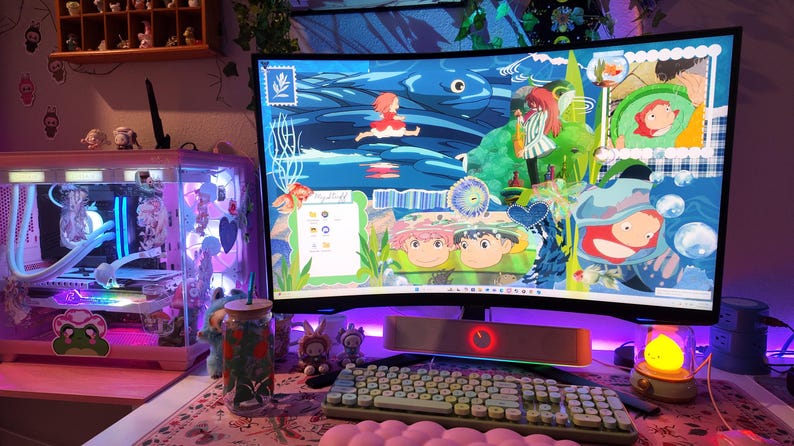 May include: A computer setup with a curved monitor displaying a colorful animated scene. A keyboard, mouse, and speaker are in front of the monitor. A desktop computer case with internal components is visible to the left. The setup is illuminated with pink and purple lighting.