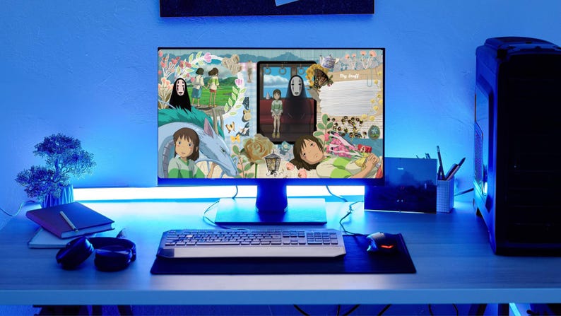 May include: A computer monitor displays a collage of images from the animated film, Spirited Away. The desk setup includes a keyboard, mouse, and a PC tower. The scene is illuminated with blue LED lighting, creating a cool, modern aesthetic.