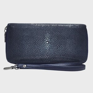 Könnte beinhalten: Eine rechteckige marineblaue Clutch mit einer texturierten Rochenhaut-Optik und einem markanten zentralen Muster aus größeren, helleren Perlen. Die Geldbörse verfügt über eine passende marineblaue Handschlaufe aus Leder mit einem silbernen Metallverschluss.