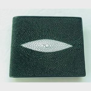 Peut inclure: Un portefeuille vert foncé avec une surface texturée et un motif ovale blanc au centre. Le portefeuille est rectangulaire et semble être fait d'un matériau durable, adapté pour transporter des cartes et de l'argent.