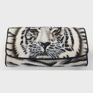 Puede incluir: Un bolso de mano blanco y negro con un diseño detallado de cara de tigre. El bolso tiene una superficie texturizada y un borde negro. Los ojos del tigre son rojos y el diseño está centrado en la parte delantera.