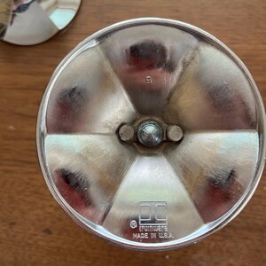 May include: Close-up of a silver metal object with a circular base and a central, rounded post. The base is divided into six sections. The text "IRWINWARE MADE IN U.S.A." is visible. The number "5" is stamped on the object.