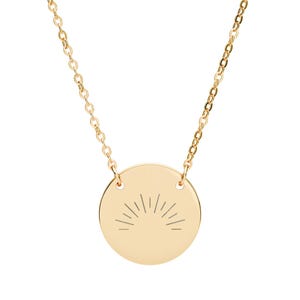 May include: A gold-colored necklace featuring a circular pendant with a sunburst design. The pendant is connected to a delicate chain. The necklace is a simple, elegant piece of jewelry.