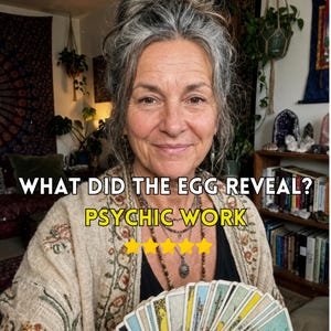 Peut inclure: Une personne aux cheveux gris portant un cardigan beige à motifs et des colliers superposés, tenant un éventail de cartes de tarot. Le texte indique : WHAT DID THE EGG REVEAL? PSYCHIC WORK, accompagné de cinq étoiles jaunes.