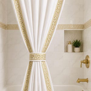 May include: A white shower curtain featuring a gold Greek key pattern along the vertical edges and a matching tieback. The curtain hangs from a gold rod with rings, positioned above a white bathtub with gold fixtures and a shower head.