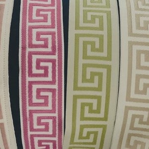 May include: A collection of eight vertical fabric trim strips featuring a repeating Greek key pattern. The colors include pale pink, dusty rose, magenta, lime green, cream, beige, metallic gold, and black with gold, all arranged side by side.