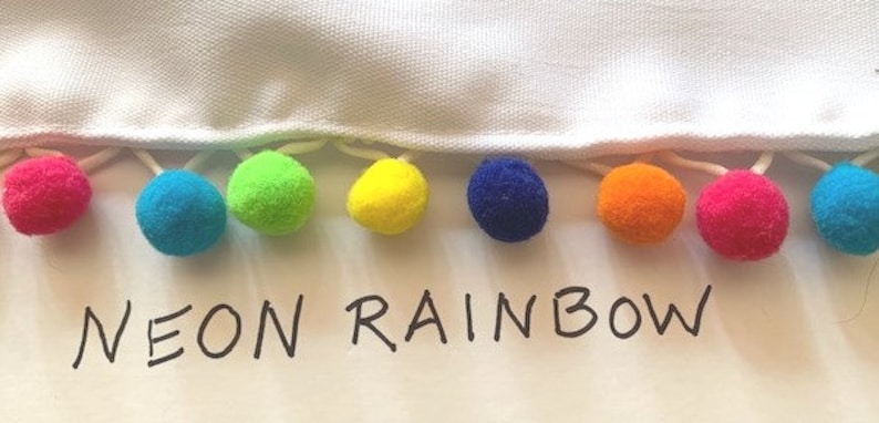 May include: A white fabric with a row of colorful pom-poms in a rainbow pattern. The text "NEON RAINBOW" is written below the pom-poms.