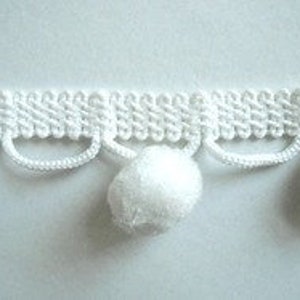 May include: White pom pom trim with a woven base and a row of pom poms hanging down.