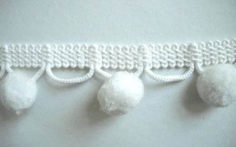 May include: White pom pom trim with a woven base and a row of pom poms hanging down.