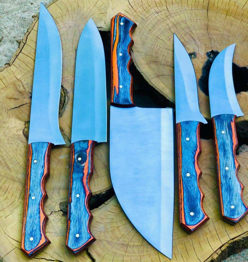 May include: A collection of six kitchen knives with stainless steel blades and blue and orange wood grain handles. The knives are displayed on a wooden surface, including a cleaver, highlighting their different blade shapes and sizes.