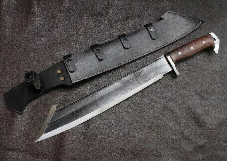 May include: A large, silver-bladed knife with a dark wooden handle and a black leather sheath. The knife has a wide blade and a curved tip. The sheath has three straps with buckles.