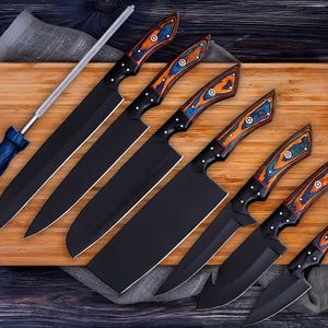 May include: A collection of six black kitchen knives with decorative wooden handles in shades of blue, orange, and white. The knives are displayed on a wooden board with a sharpening steel. The blades are black.
