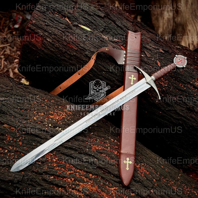 May include: A medieval-style sword with a silver blade and a brown leather handle and sheath. The sheath features a gold cross design. The sword rests on a dark wooden surface. The sword's handle has a red and white emblem.