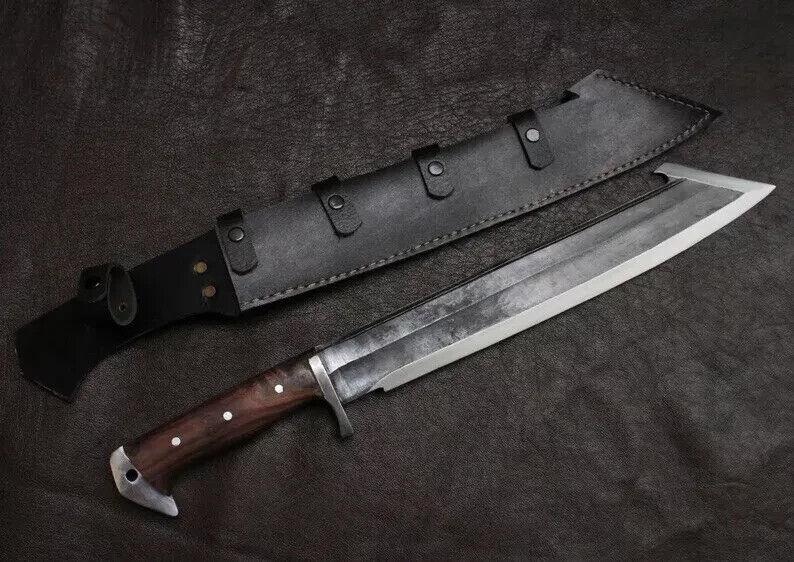 May include: A large, silver-bladed knife with a dark wooden handle and a black leather sheath. The knife has a wide blade and a sturdy design, suitable for outdoor or survival use. The sheath features multiple straps for secure storage.