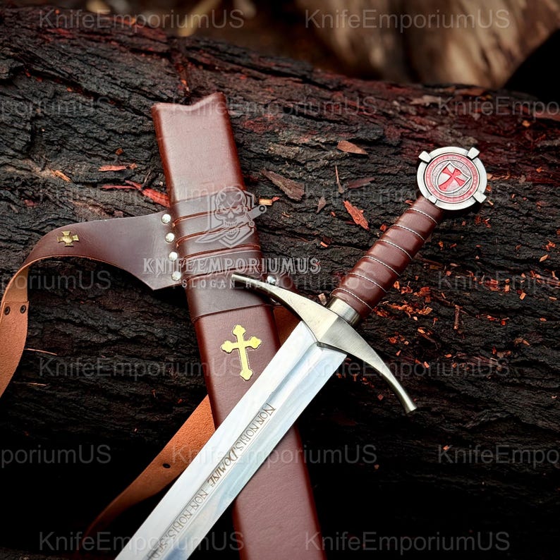 May include: A medieval sword with a brown leather-wrapped handle and a silver blade, resting in a brown leather sheath. The hilt features a red and white emblem. The sheath has a gold cross and the text "NON NOBIS DOMINE NON NOBIS".