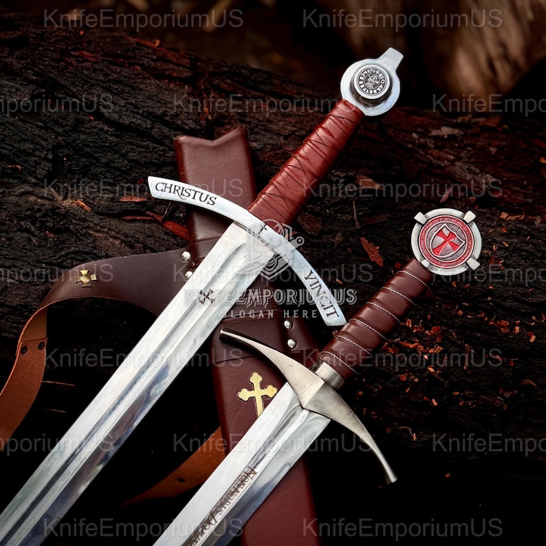 May include: Two medieval swords with brown leather-wrapped handles and silver blades. One sword has the word "CHRISTUS" and "VINCIT" etched on the blade. A brown leather sheath with a gold cross is visible.
