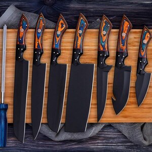 May include: A collection of eight black kitchen knives with wooden handles, decorated with blue and orange patterns, presented on a wooden board. Includes a sharpening steel. Knives vary in size and shape.
