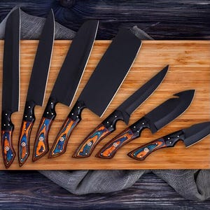May include: A collection of seven black kitchen knives with patterned handles in blue, orange, and brown, displayed on a wooden chopping board. Includes a sharpening steel with a blue handle. Knives vary in size and shape.