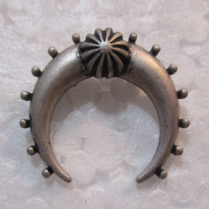 May include: A silver crescent moon shaped ring with a starburst design in the center. The ring is decorated with small beads around the edge.