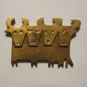 May include: A gold-colored metal ornament depicting four stylized cows standing side-by-side.