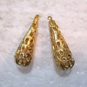 May include: Two gold filigree teardrop shaped earring pendants. The pendants are hollow and have a delicate, intricate design.