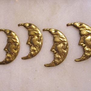 Op de afbeelding: Vier antieke goudkleurige halve maan bedels met een profiel van een mannengezicht. De bedels zijn in een rij gerangschikt, elk met een gedetailleerd gezicht en baard. De achtergrond is een licht, getextureerd oppervlak.