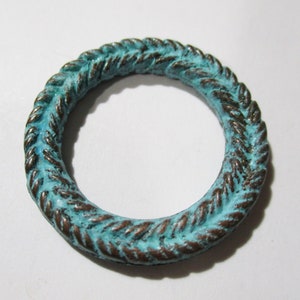 Könnte beinhalten: Ein türkisfarbener Metallring mit einem seilartigen Design. Der Ring ist aus Metall und hat eine Used-Look-Oberfläche.