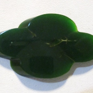 Può includere: Un oggetto decorativo a forma di nuvola, di colore verde scuro. L'oggetto ha una superficie liscia e lucida e una forma organica unica. Il colore è un verde intenso e ricco, e l'oggetto sembra essere fatto di un materiale solido.