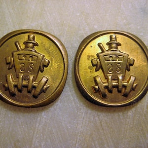 May include: Two gold-colored metal buttons with a design of a carriage with a driver and the number 28 on the side.