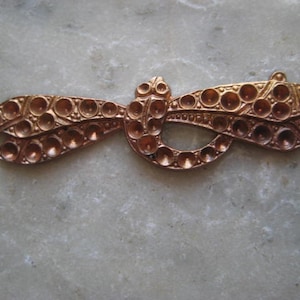 May include: A copper-colored metal dragonfly design with a raised, textured surface. The dragonfly has a rounded body and two sets of wings with small, circular details.