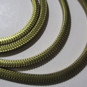 May include: A gold-toned snake chain necklace. The chain is made of interlocking links that create a smooth, flowing design.