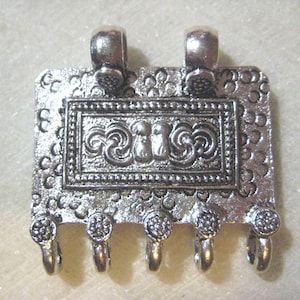 May include: Silver-toned metal pendant with a rectangular design featuring an ornate, embossed pattern. The pendant has five loops at the bottom.