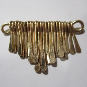 May include: Gold-toned metal pendant with a fringe design. The pendant is made of multiple small, connected loops that form a cascading fringe.