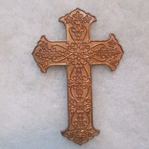 Peut inclure: Une croix décorative, ornée, de couleur cuivre avec des motifs floraux complexes.