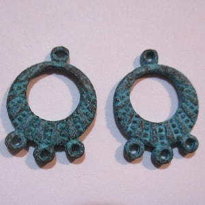 May include: Two antique-looking, teal-colored metal earrings with a circular design and three small loops hanging from the bottom.