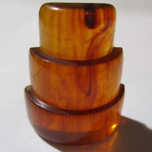 Peut inclure: Un bouton en bakélite à trois niveaux de couleur ambre avec une finition lisse et brillante.