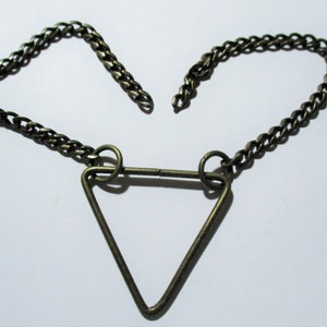 May include: A gold-toned chain necklace with a triangular pendant. The chain is made of small, linked circles. The pendant is a simple triangle shape with rounded corners.