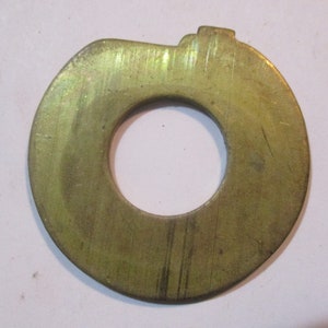 Könnte beinhalten: Eine goldfarbene Metall-Unterlegscheibe mit leicht unregelmäßiger Form und glatter Oberfläche.