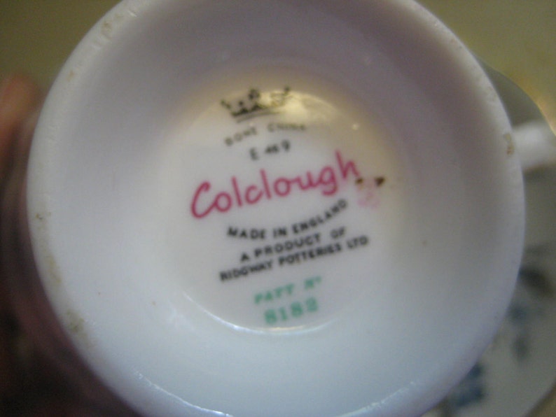 May include: Close-up of the bottom of a white teacup with a pink and black logo that reads "Colclough" and the text "Made in England A product of Ridgway Potteries Ltd.  Pat. No. 8188".