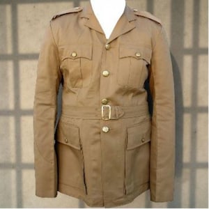 May include: Tan military-style jacket with four front pockets, shoulder epaulets, and gold-colored buttons. The jacket features a belted waist with a gold buckle and is made of a sturdy fabric.