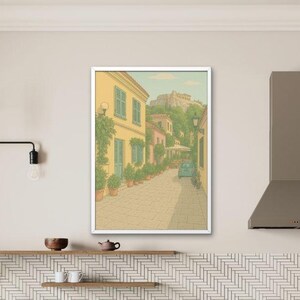 May include: A framed art print depicting a European street scene with yellow buildings, blue shutters, and potted plants. The artwork hangs above a kitchen counter with dark wood cabinets, a white countertop, and a herringbone tile backsplash.