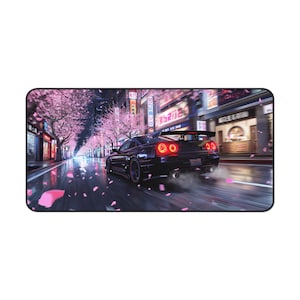 Puede incluir: Una alfombrilla de ratón rectangular con un coche deportivo negro que corre por una calle mojada bordeada de cerezos en flor. Las luces traseras rojas del coche brillan, con tiendas japonesas y letreros de neón de fondo.