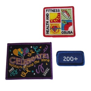 May include: Three embroidered patches. One square patch with the words "HEALTH AND FITNESS" and images of a sun, a sandwich, a heart, and an apple. A rectangular patch with the word "CELEBRATE!" and balloons. A blue patch with "200+".